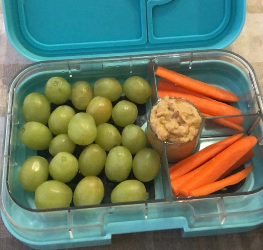 Desayuno de hummus con palitos de zanahoras y uva